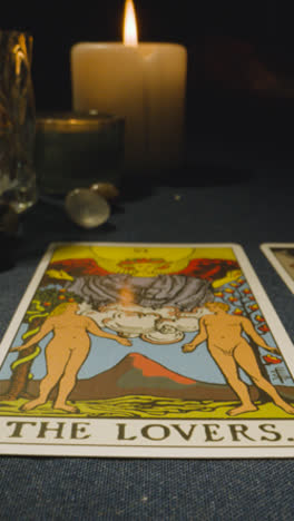 Vertical-Video-Close-Up-Shot-Of-Person-Giving-Tarot-Card-Reading-Laying-Down-The-Lovers-Card-On-Table